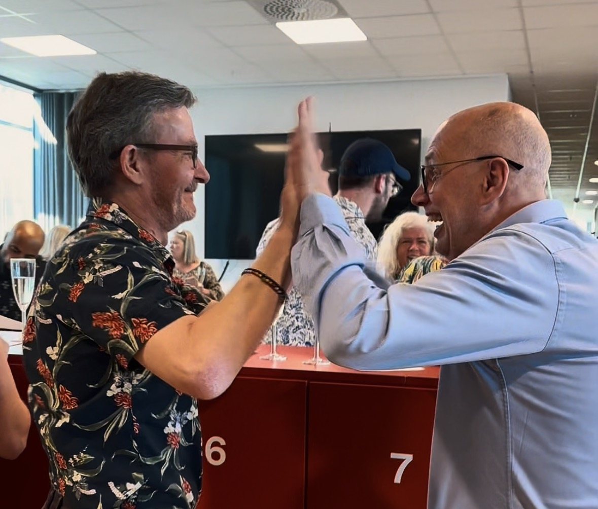 Two men high-five in the middle of the mingle